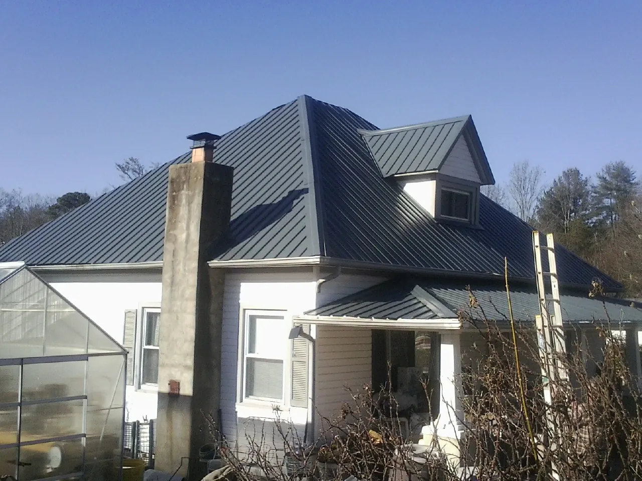 Dark blue standing seam metal roof on a white farmhouse with dormer — Slate & Tile Roof Repair by Roofing Brothers in Clarington