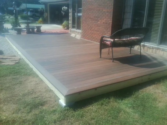 New wood deck and wicker chair beside a brick house in Clarington