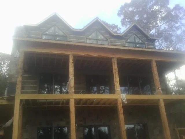 Dormers and porch framing on a large log home under construction — Roof Coating work by our crew in Clarington