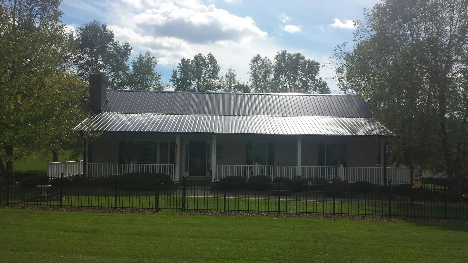 Gray metal roof on a brick ranch with a full width front porch — Gutter Guard Installation work by our crew in Clarington
