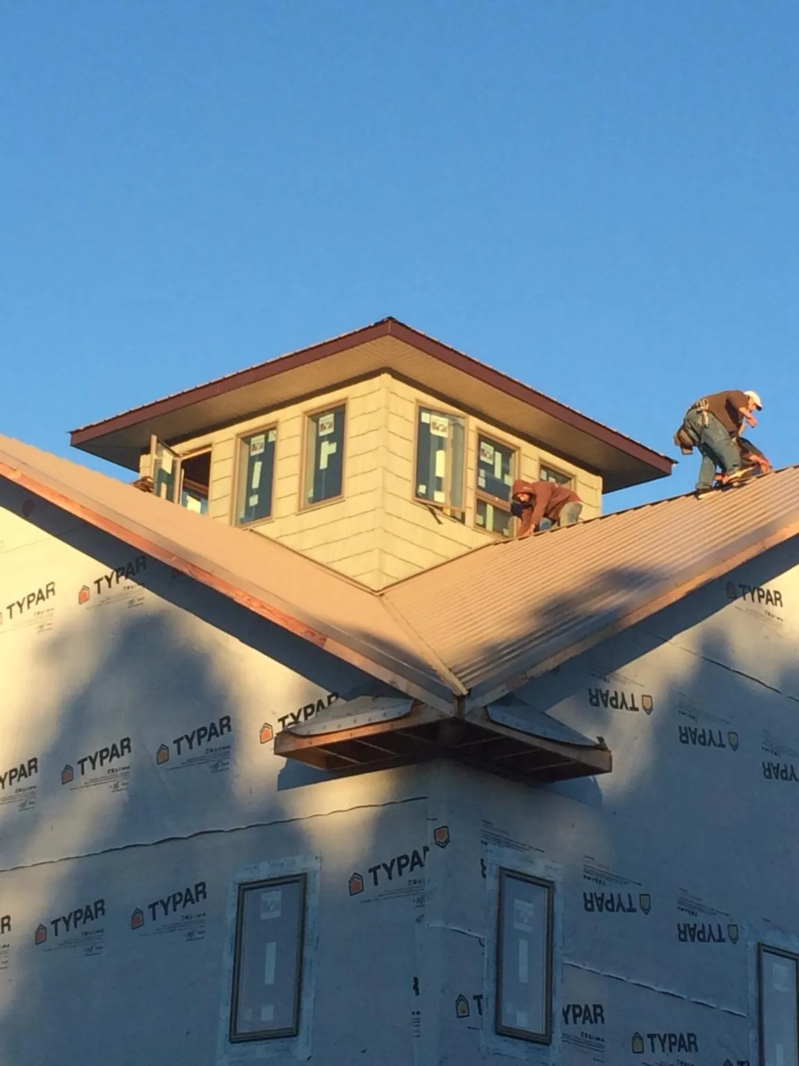 Roofers working around a rooftop cupola on a new metal roof at sunset — Roof Waterproofing in Clarington by Roofing Brothers